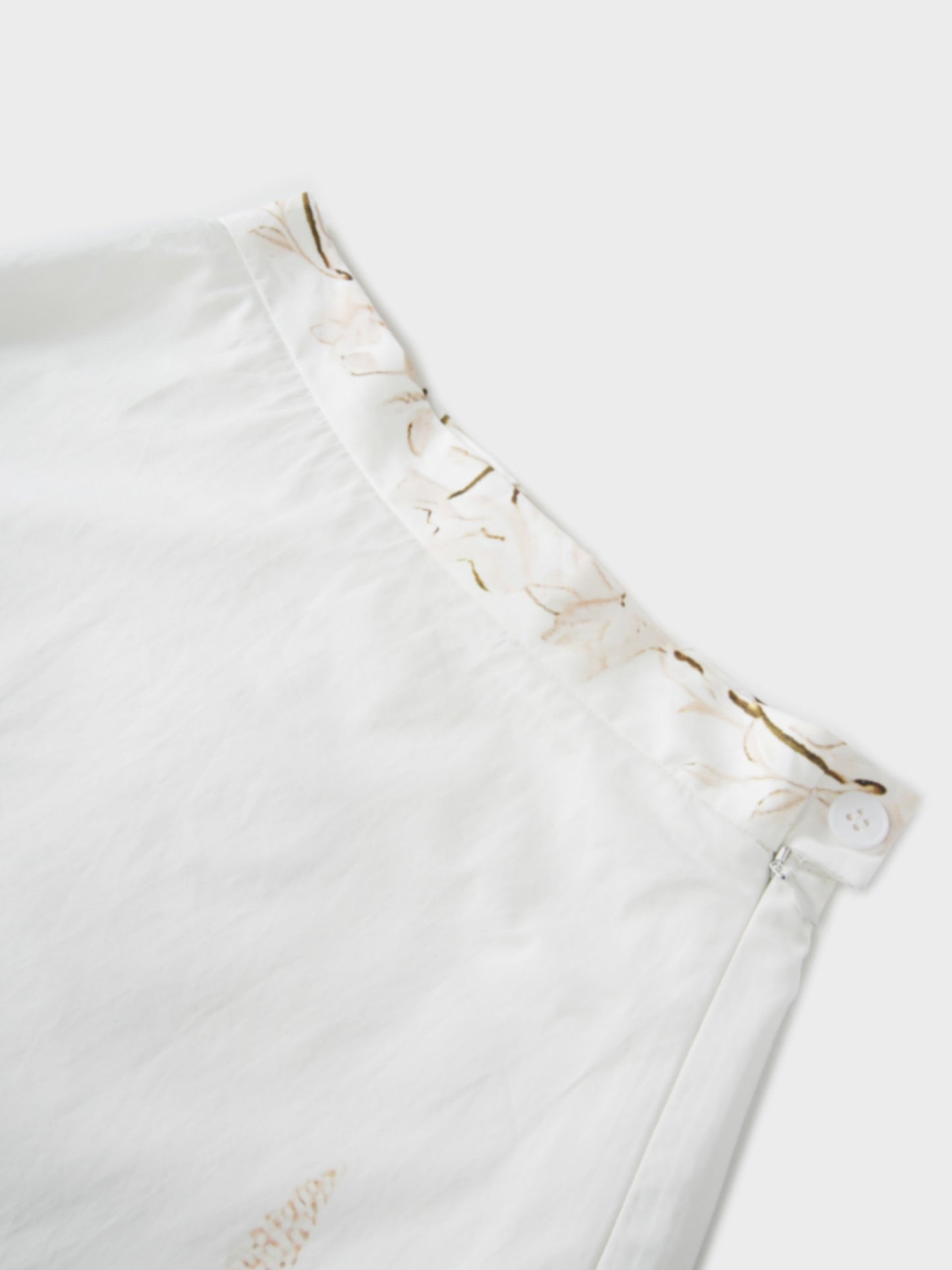 Close-up of a white garment with ruffled details on a light background