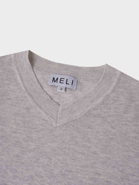 Close-up of a gray sweater with a visible brand label on a light gray background