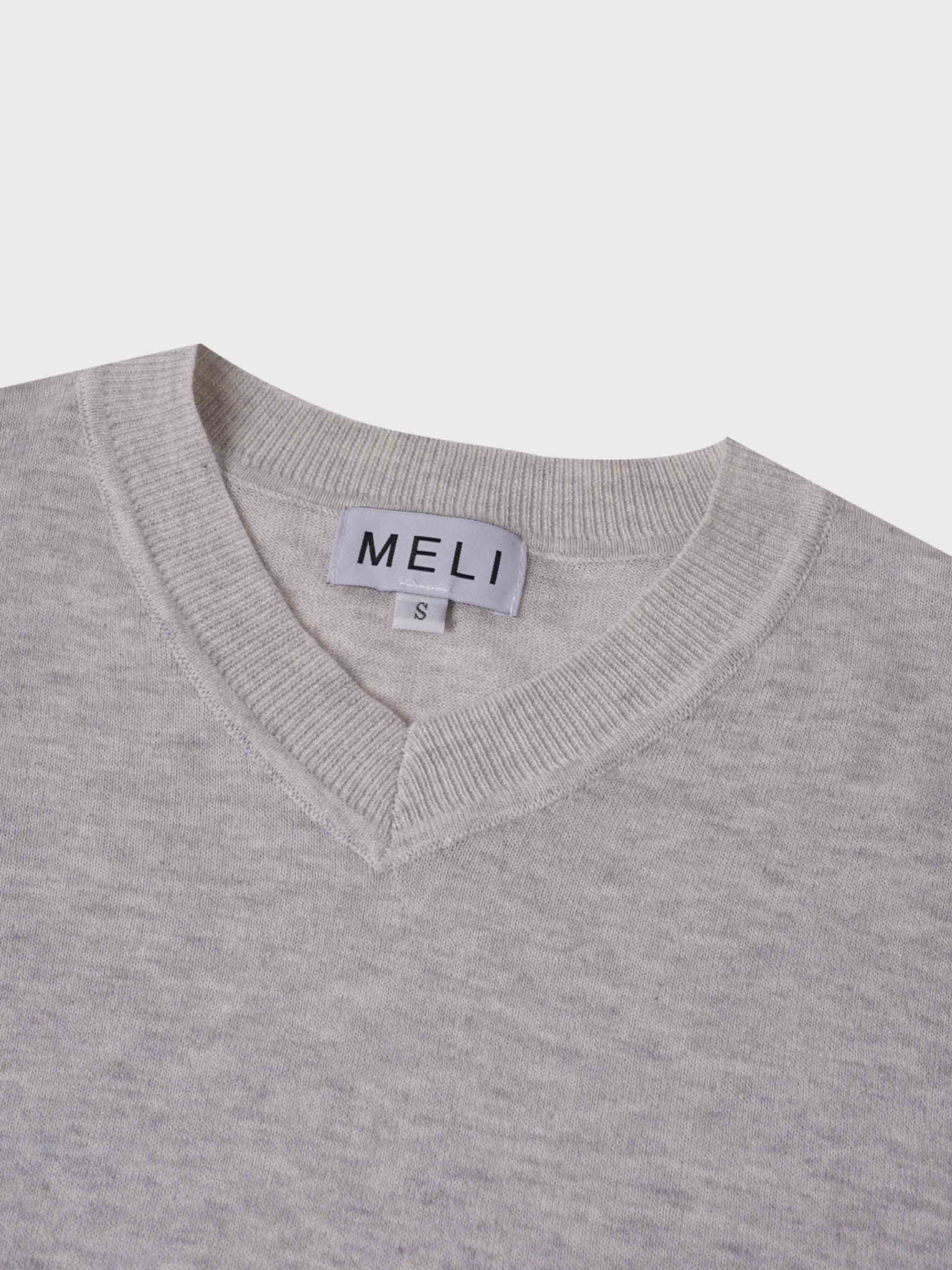 Close-up of a gray sweater with a visible brand label on a light gray background