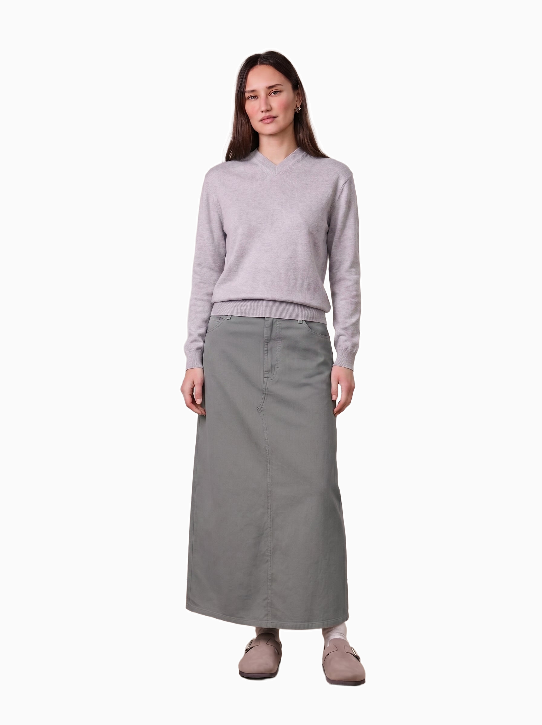 Woman wearing a light gray sweater and long skirt on a white background