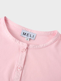 Close-up of a pink ribbed garment with 'MELI' label on a light gray background