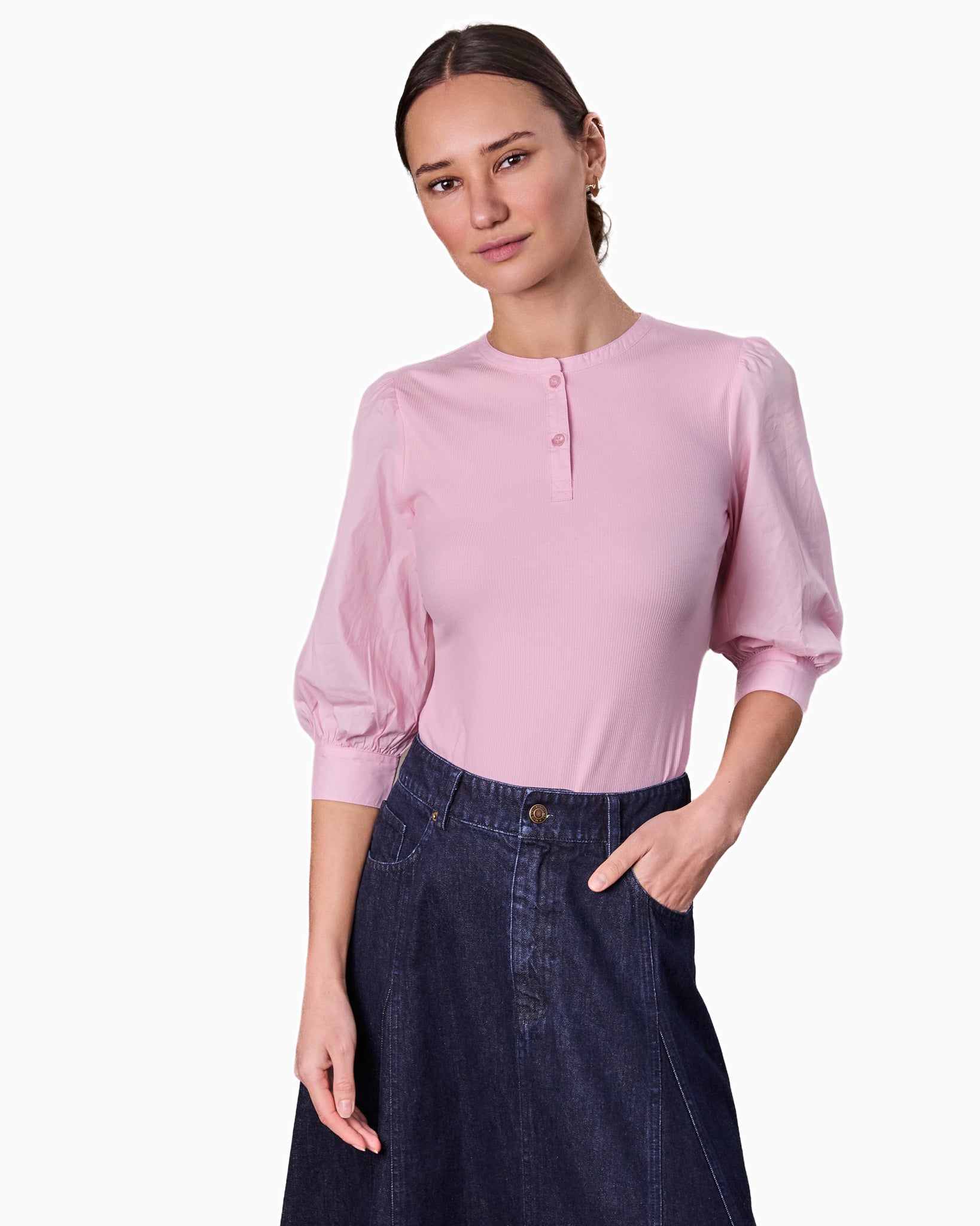 Woman wearing a pink blouse and dark blue jeans on a white background