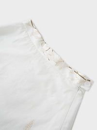 Close-up of a white garment with ruffled details on a light background
