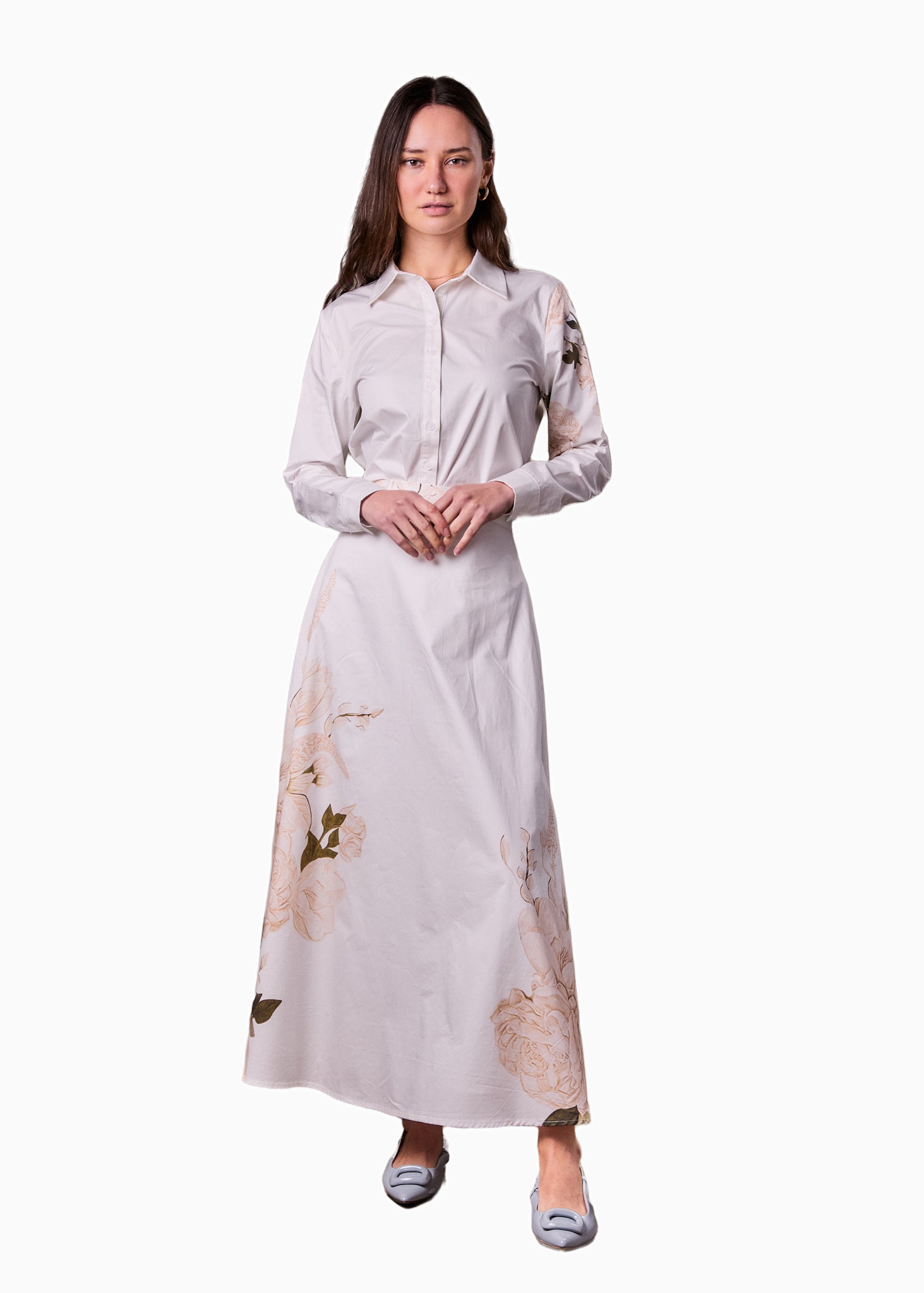 Woman wearing a long, light-colored dress with floral patterns on a white background
